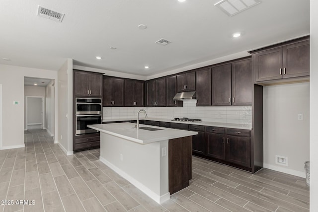 9416 E Sequence Ave, Mesa, AZ 85212 - kitchen with appliances with stainless steel finishes, wood finish floors, decorative backsplash, dark brown cabinetry, and recessed lighting