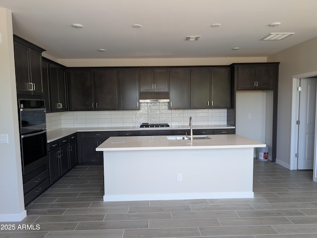 9416 E Sequence Ave, Mesa, AZ 85212 - kitchen featuring wood finish floors, under cabinet range hood, tasteful backsplash, gas cooktop, and a center island with sink