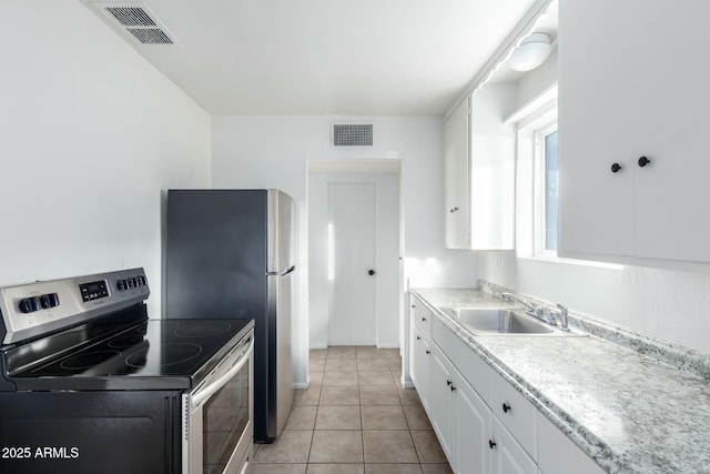 kitchen featuring stainless steel electric range oven, sink, white cabinets, and light tile patterned floors