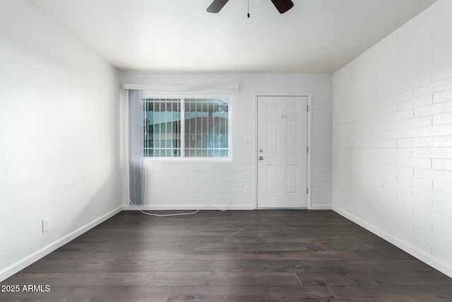 unfurnished room with ceiling fan, brick wall, and dark hardwood / wood-style flooring