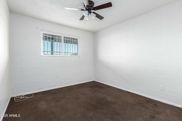 unfurnished room with ceiling fan, a textured ceiling, brick wall, and dark carpet