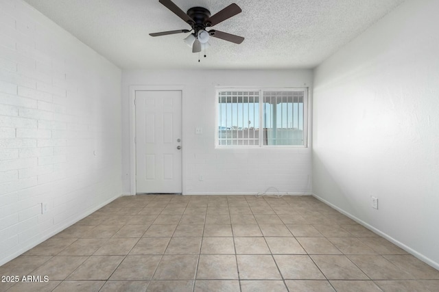 tiled empty room with a textured ceiling, brick wall, and ceiling fan