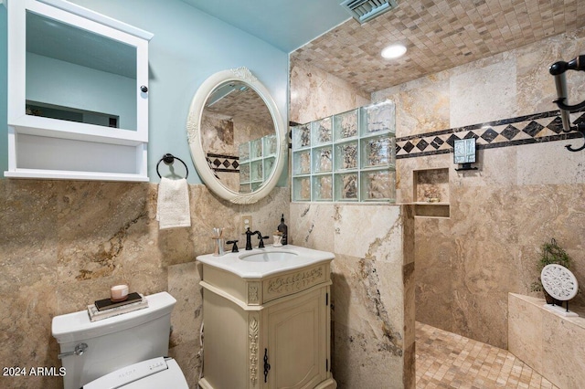 bathroom with vanity, a tile shower, and tile walls