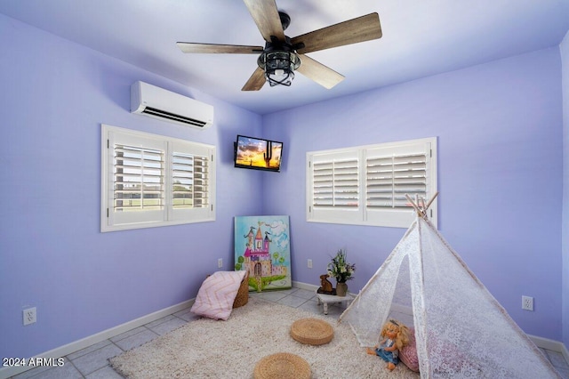 rec room with a wall mounted air conditioner, ceiling fan, and light tile patterned flooring