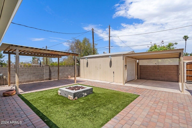 view of yard featuring a patio, an outdoor fire pit, and a storage unit