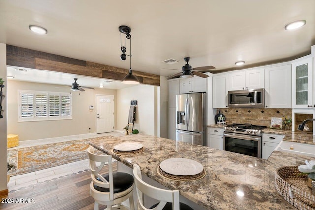 kitchen featuring pendant lighting, stainless steel appliances, white cabinets, ceiling fan, and sink