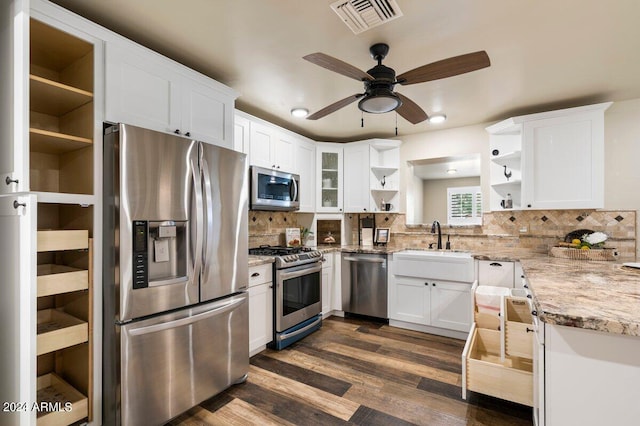 kitchen featuring stainless steel appliances, light stone countertops, backsplash, ceiling fan, and dark hardwood / wood-style floors