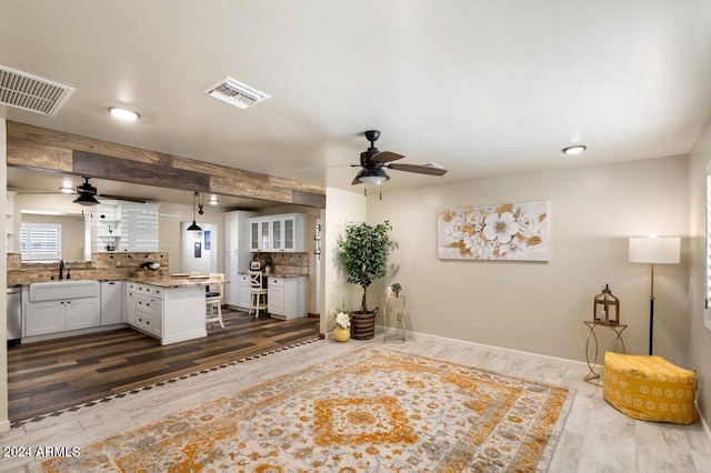 unfurnished living room with ceiling fan, sink, dark hardwood / wood-style flooring, and beamed ceiling