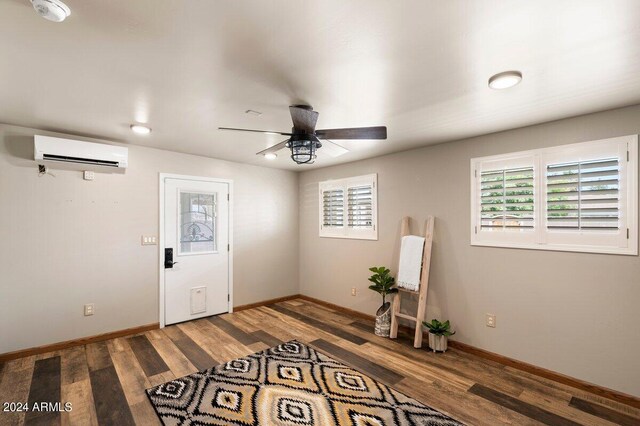 interior space featuring ceiling fan, a wall unit AC, and wood-type flooring