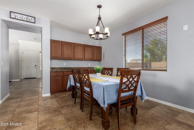 tiled dining room with a chandelier and baseboards