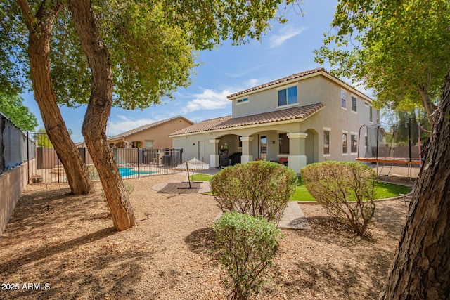 rear view of house featuring a patio, a fenced in pool, a fenced backyard, stucco siding, and a trampoline