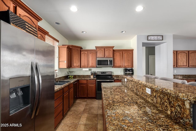 kitchen with recessed lighting, dark stone counters, appliances with stainless steel finishes, and a sink