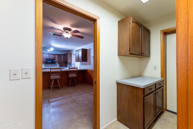 kitchen with ceiling fan, light tile patterned flooring, and black microwave