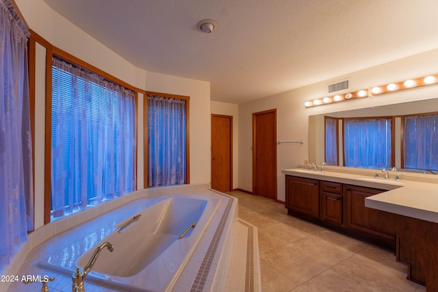 bathroom featuring vanity, a relaxing tiled tub, a textured ceiling, and tile patterned floors