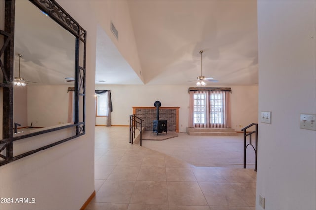 interior space with a wood stove, ceiling fan, and vaulted ceiling