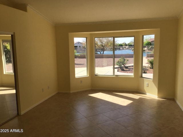 tiled spare room featuring baseboards and ornamental molding