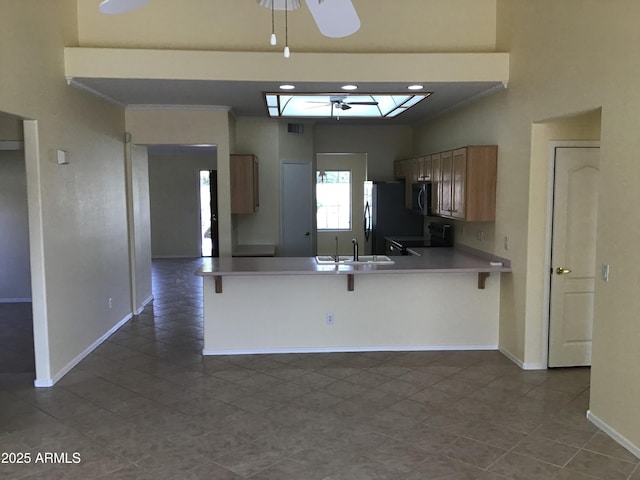 kitchen featuring baseboards, ceiling fan, electric stove, dark tile patterned flooring, and a skylight