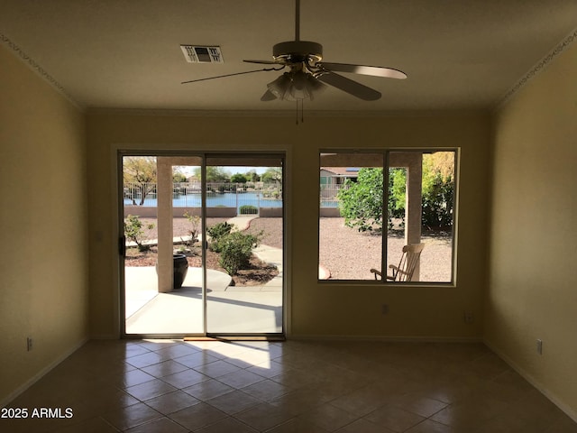 tiled empty room featuring a water view, visible vents, a ceiling fan, and a healthy amount of sunlight