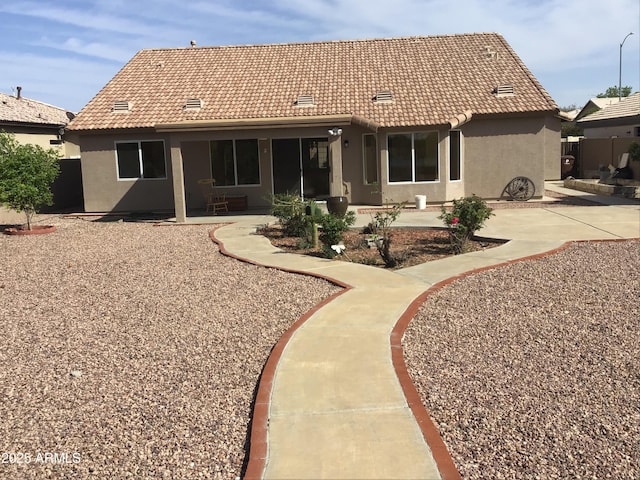 back of property featuring a tiled roof, a patio area, and stucco siding