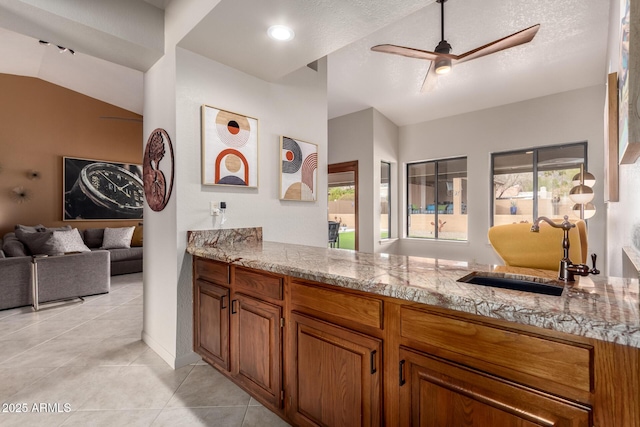 kitchen featuring light tile patterned floors, a healthy amount of sunlight, a sink, and brown cabinets