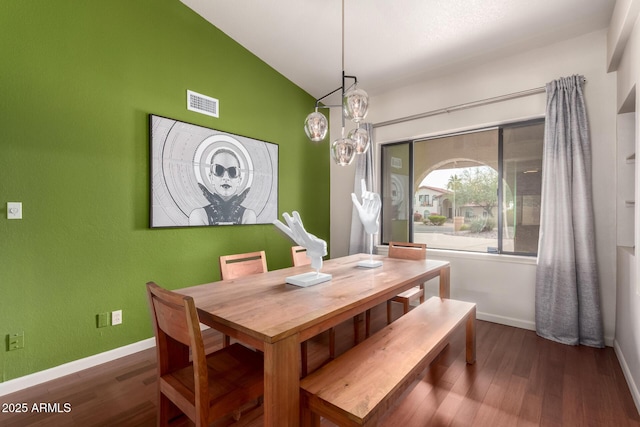 dining space with baseboards, visible vents, vaulted ceiling, and wood finished floors