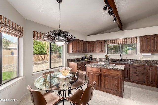 kitchen featuring vaulted ceiling with beams, light tile patterned floors, a sink, a center island, and dark stone countertops