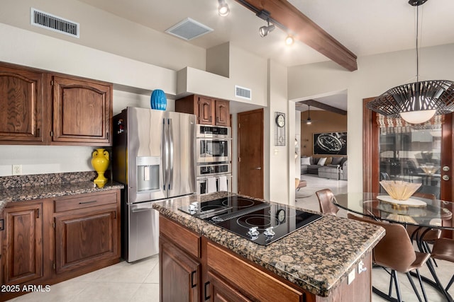 kitchen featuring dark stone counters, stainless steel fridge, visible vents, and black electric cooktop