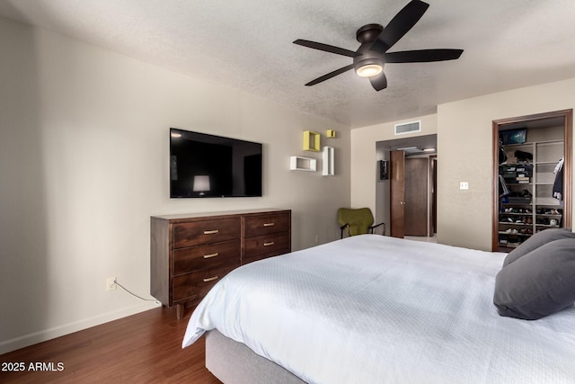 bedroom with baseboards, visible vents, dark wood finished floors, ceiling fan, and a textured ceiling