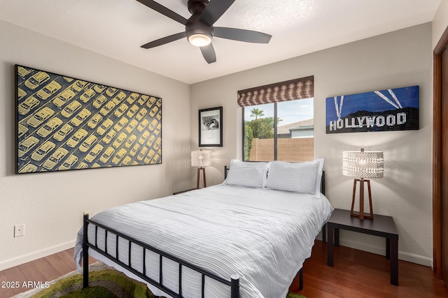 bedroom featuring ceiling fan, baseboards, and wood finished floors