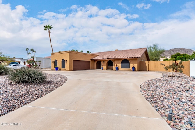 mediterranean / spanish-style house with a garage, fence, concrete driveway, a gate, and stucco siding