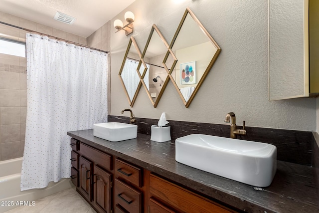 bathroom featuring a textured wall, a sink, visible vents, and tile patterned floors