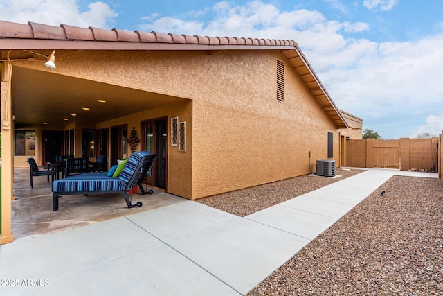 view of property exterior with cooling unit, a patio area, fence, and stucco siding