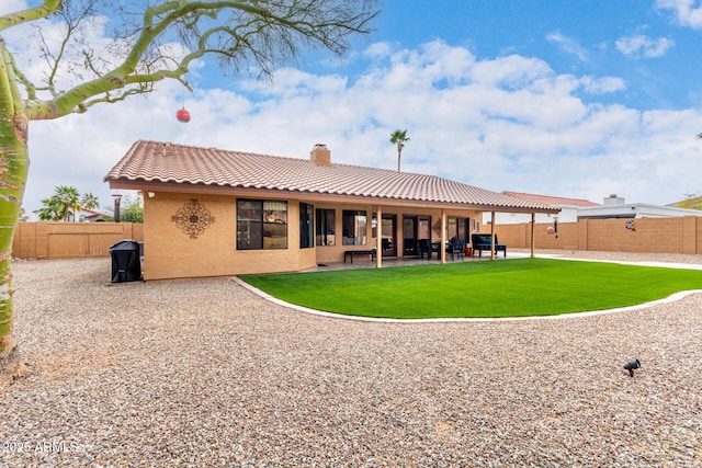 back of house featuring a patio, a tile roof, a chimney, a yard, and stucco siding