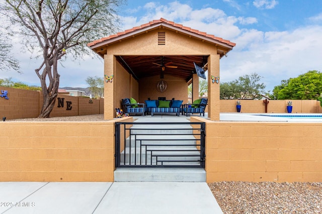 view of patio with a fenced front yard, a gate, an outdoor living space, and a ceiling fan