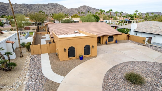 view of front facade featuring a fenced backyard, a mountain view, and stucco siding