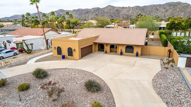 view of front of house featuring fence private yard, a mountain view, concrete driveway, and stucco siding