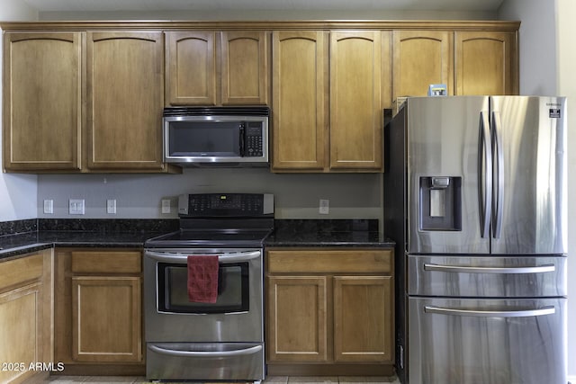 kitchen featuring stainless steel appliances and dark stone countertops