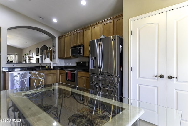 kitchen featuring stainless steel appliances, sink, and dark stone countertops