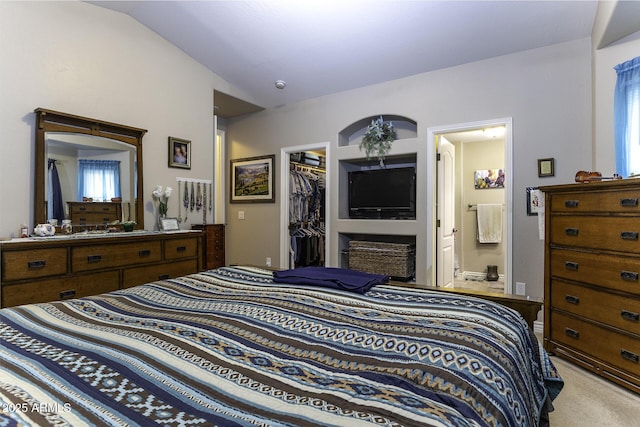 bedroom featuring connected bathroom, a walk in closet, vaulted ceiling, light carpet, and a closet