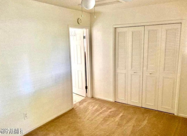 unfurnished bedroom featuring ceiling fan, a closet, and light colored carpet