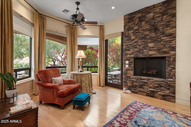 11821 S Tuzigoot Ct, Phoenix, AZ 85044 - living area with visible vents, baseboards, a stone fireplace, a ceiling fan, and wood finished floors