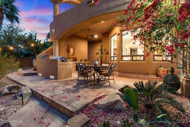 11821 S Tuzigoot Ct, Phoenix, AZ 85044 - patio terrace at dusk featuring fence, an outdoor kitchen, a ceiling fan, and outdoor dining space