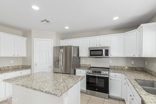 3910 W Goldmine Mountain Dr, San Tan Valley, AZ 85144 - kitchen featuring stainless steel appliances, white cabinets, light tile patterned flooring, a center island, and light stone counters