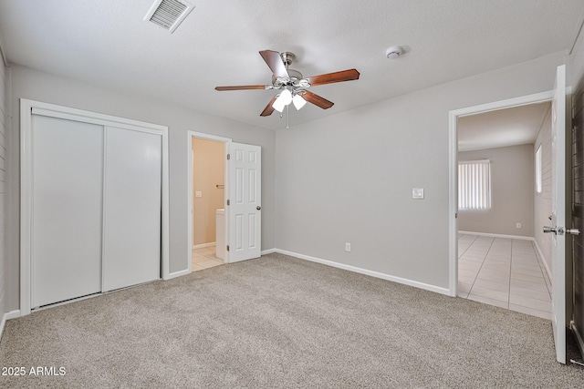 unfurnished bedroom featuring visible vents, tile patterned floors, baseboards, a closet, and carpet flooring