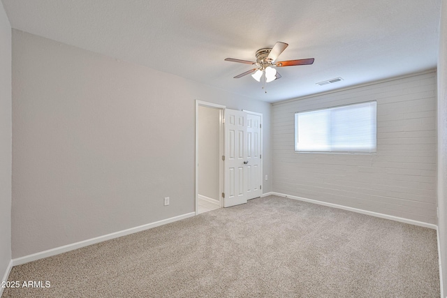 unfurnished room with carpet floors, a ceiling fan, baseboards, and visible vents