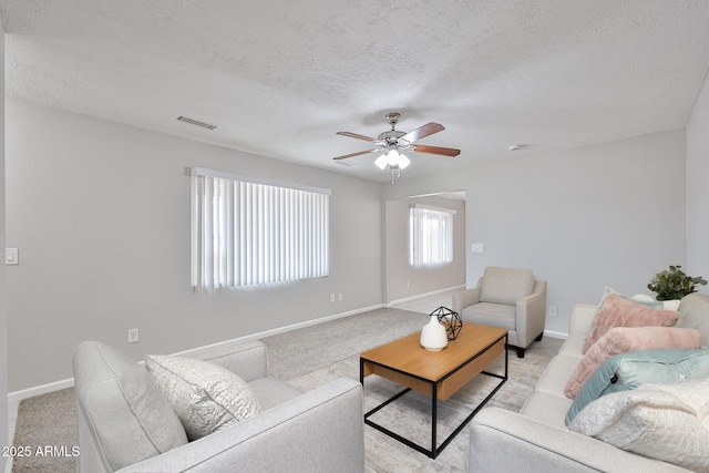 living area with visible vents, baseboards, ceiling fan, and light carpet