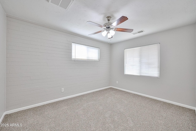 carpeted spare room featuring baseboards, visible vents, and ceiling fan