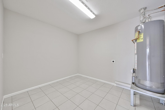 below grade area featuring light tile patterned flooring, baseboards, and water heater
