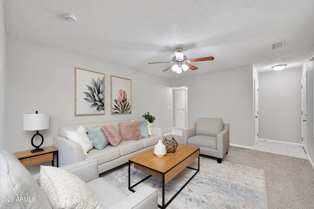 living area with visible vents, baseboards, ceiling fan, light colored carpet, and a textured ceiling
