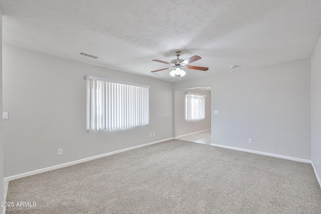 carpeted empty room with a ceiling fan, baseboards, visible vents, and a textured ceiling